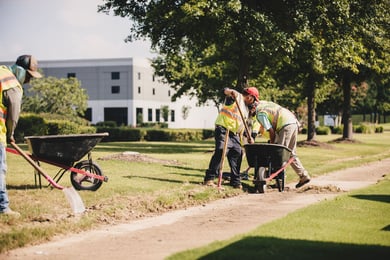 Men in yellow safety vests with shovels and wheelbarrows