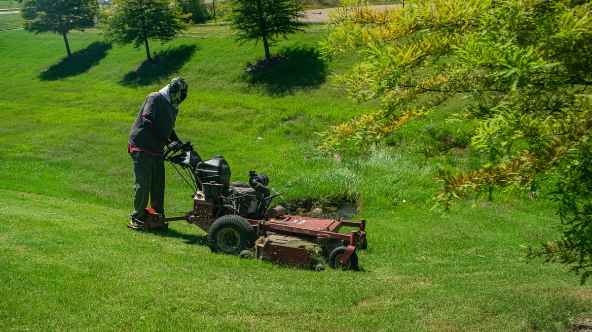 commercial landscaping crew mows grass on hill