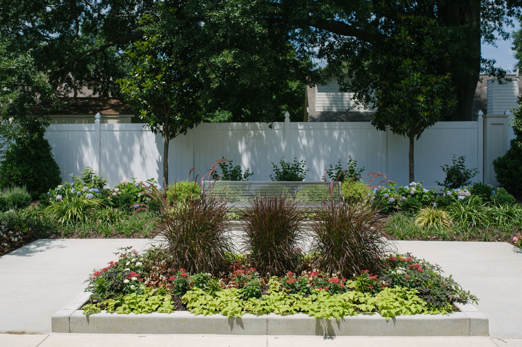 commercial landscape with trees, shrubs, flowers, and bench