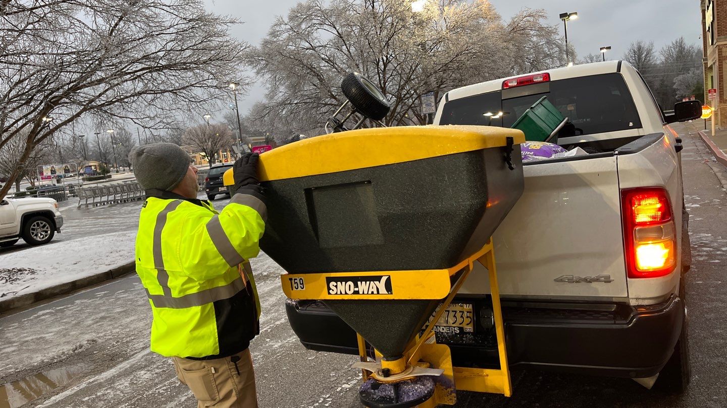 An member of the Michael Hatcher & Associates snow and ice management team inspects a truck spreader used to apply ice melt at a commercial maintenance property.