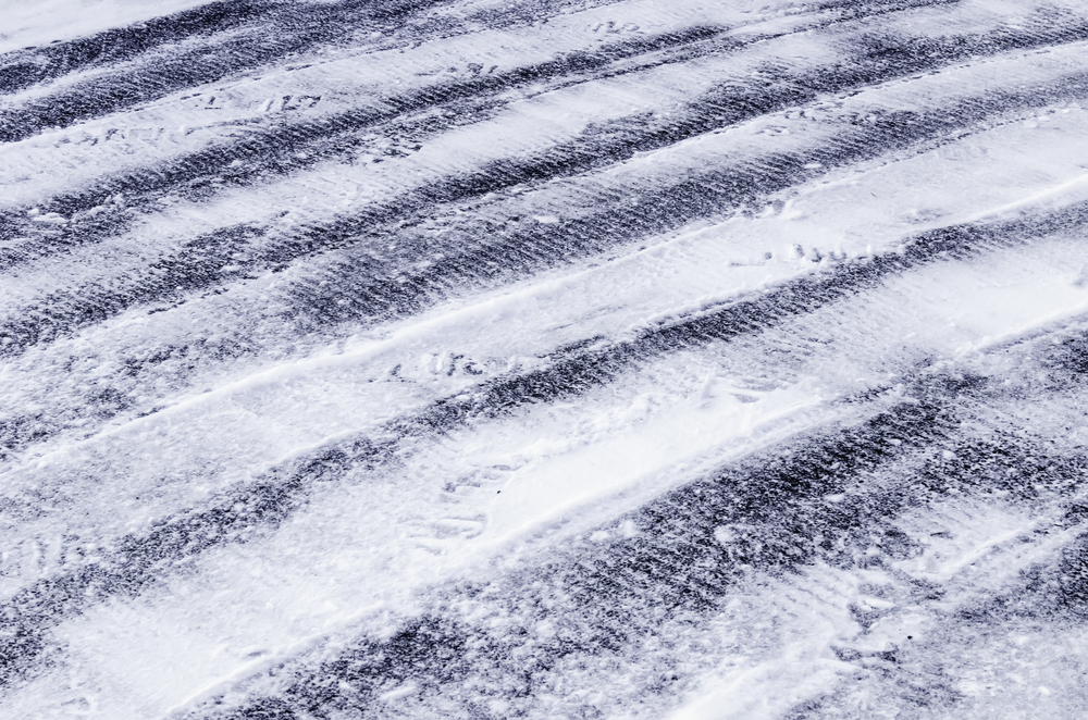 Winter abstract Rows of tread marks from tires of small plow in snow on asphalt driveway in northern Illinois